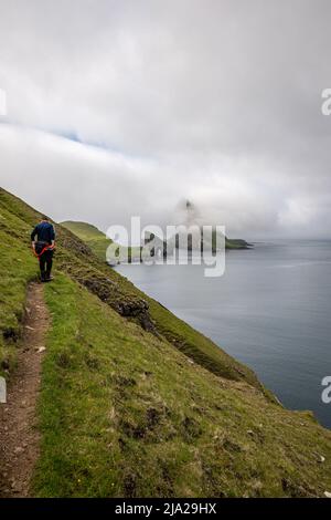 Ein Tourist auf der Einbahnstrecke zum Aussichtspunkt der Felsformation Drangarnir auf Vagar, Färöer-Inseln Stockfoto