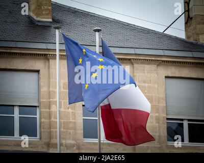 Bild einer französischen Flagge, die neben einer europäischen Flagge mit ihren Sternen steht. Frankreich ist eines der Gründungsmitglieder der Europäischen Union Stockfoto