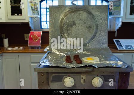 Kompakter Grill mit Speck und Eiern, der auf der Folienoberfläche in der modernen Küche aus der Mitte des Jahrhunderts im mittelalterlichen Hammond Castle BU von 1926 zubereitet wird Stockfoto