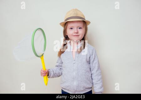 Kleine und schöne blonde Mädchen in einem Strohhut hält ein Schmetterlingsnetz in der Hand und fängt Schmetterlinge Studio weißen Hintergrund.Fröhliche weibliche Kind Stockfoto