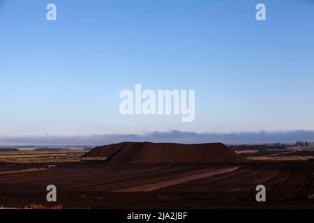 Industriegebiet, in dem schwarzer Torf abgebaut wird, Landschaft in der Natur auf dem Gebiet der Torfgewinnung Stockfoto