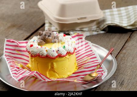 Bento Lunchbox Korean Cake, Mini Buttercream Cake serviert auf Lunch Box Paket, auf Holztisch Stockfoto