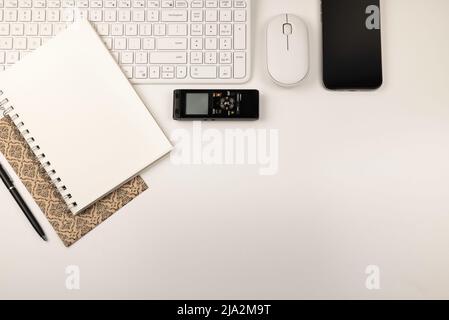 Weiße Tastatur, Maus und Notizblock mit schwarzem Stift und Voice Recorder liegen flach auf weißem Hintergrund Stockfoto