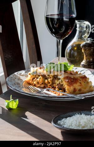 Eine Portion Lasagne Roll Ups serviert mit Rotwein garniert mit Basilikum. Stockfoto