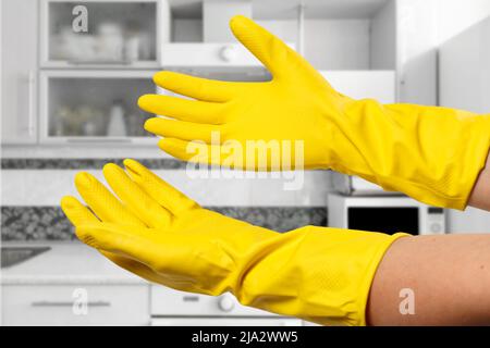 Nahaufnahme von Frauenhänden mit gelben Gummihandschuhen. Stockfoto