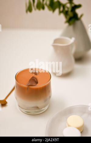 Iced Latte Coffee, ein Glas Kaffee mit Milch auf einem minimalen weißen Tischhintergrund. Iced Caramel Latte Stockfoto