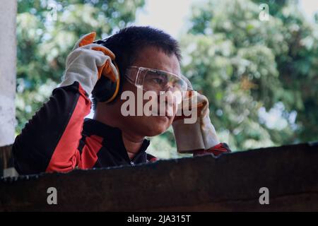 Ein erfahrener Metallarbeiter trägt Sicherheitsausrüstung, um sich vor der Arbeit in der Werkstatt zu Hause vorzubereiten. Stockfoto