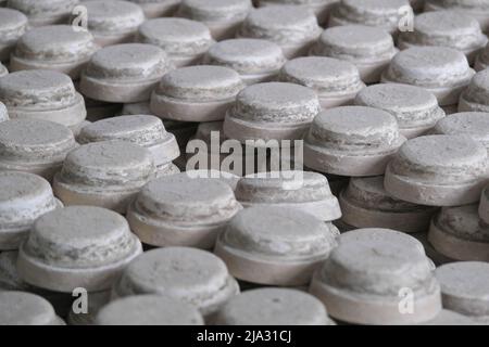 Viele Formen für die Herstellung kleiner runder Platten auf dem Gestell. Herstellung von handgefertigten Keramikbechern. Handwerk und Kleinunternehmen Konzept. Stockfoto