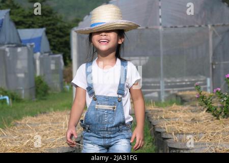 Kleines Mädchen mit Hut hilft ihrer Mutter im Garten, einer kleinen Gärtnerin. Nettes Mädchen spielt im Gemüsegarten. Stockfoto