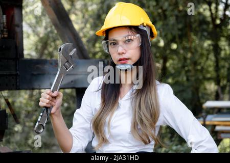 Asiatische Ingenieurin mit Industrieschlüssel in der Werkstatt. Ingenieurin Frau, die in der Fertigung arbeitet. Beruf und Bauarbeiten Stockfoto