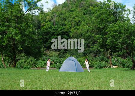 Glückliche kleine Schwestern spielen während des Sommerurlaubs auf dem Land auf einem Campingplatz zusammen. Zwei niedliche kleine Mädchen, die Spaß haben, draußen auf einem heißen spielen Stockfoto