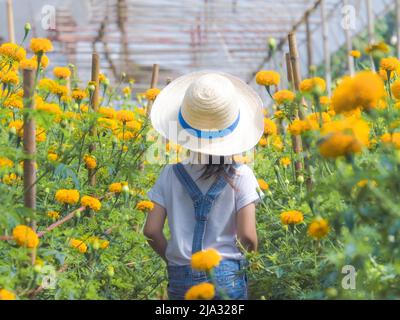 Ein kleines Mädchen mit Hut hilft ihrer Mutter im Ringelgarten, einer kleinen Gärtnerin. Nettes Mädchen spielt in einem schönen Blumengarten. Stockfoto