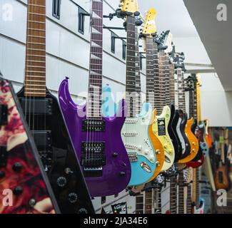 Eine Sammlung von bunten E-Gitarren, die in einem Musikgeschäft ausgestellt werden. Stockfoto