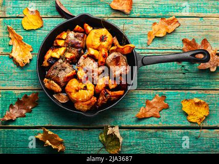 Gebratenes Schweinefleisch mit herbstlicher Quitte in einer gusseisernen Pfanne.geschmortes Fleisch Stockfoto