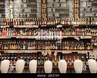 Moskau, Russland - 17. August 2018: In einer Bar in Moskau, Russland, werden verschiedene Arten von abgefülltem Bier im Regal ausgestellt. Menü im Hintergrund. Stockfoto