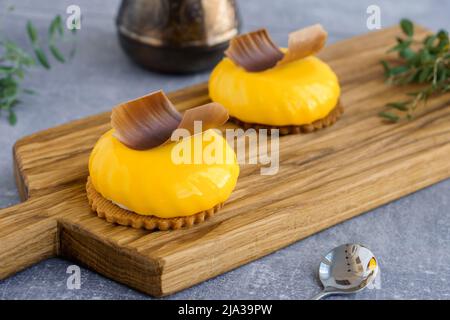 Süßes Dessert. Gelbe Pfirsichkuchen mit Schokoladenscheibe auf Holzschneidebrett und Cezve Stockfoto