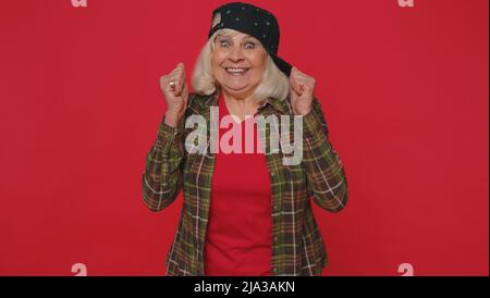 Stylische ältere Frau im Hemd, die schrie, als Geste die Fäuste hochhebend, tat ich es, um den Erfolg zu feiern Stockfoto