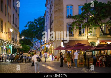 Lyon, Frankreich - 10. Mai 2022 : Touristen, die in Restaurants im Freien essen und andere, die nachts durch die Altstadt von Lyon fahren Stockfoto