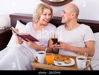 Mann, der meiner Freundin beim Frühstück etwas vorführt Stockfoto