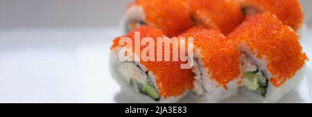 Sushi mit orange fliegendem Fischkaviar auf einem weißen Teller Stockfoto