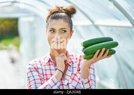 Bild einer jungen Gärtnerin mit Gurke Stockfoto