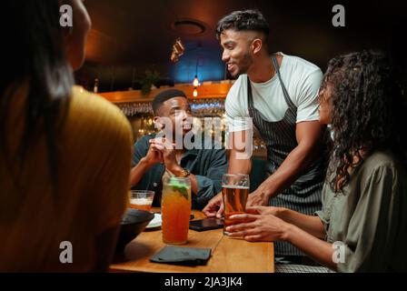 Verschiedene Gruppen von Freunden, die zum Abendessen vom Kellner serviert wurden Stockfoto