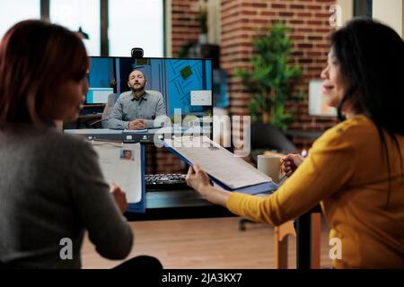 Geschäftsfrauen halten Zwischenablage lesen Rekrutierer lebenslauf Diskussion Unternehmen Einstellungsplan während der Job-Termin während Online-Videocall Meeting Konferenz in Startup-Büro. Telefonkonferenz Stockfoto