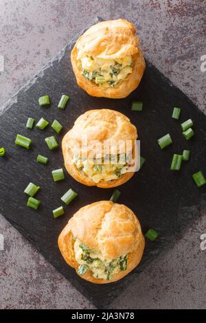 Vorspeise für den Urlaub Profiteroles mit Eiersalat aus der Nähe auf einem Schieferbrett auf dem Tisch. Vertikale Draufsicht von oben Stockfoto