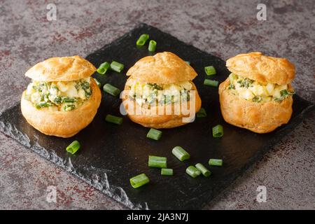 Leckere Vorspeise proliteroles gefüllt mit Eiersalat close-up auf einem Schieferbrett auf dem Tisch. Horizontal Stockfoto