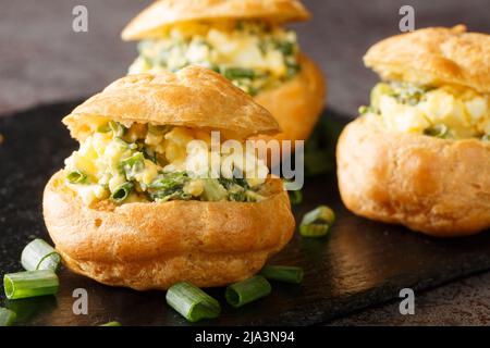 Snacks Profiteroles gefüllt mit Eiersalat Nahaufnahme auf einem Schieferbrett auf dem Tisch. Horizontal Stockfoto