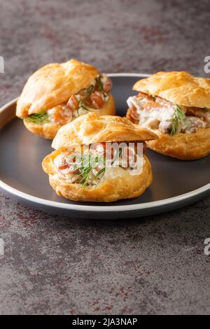 Profiterolen gefüllt mit Pilzen in Sahnesauce, Zwiebeln und Kraut aus nächster Nähe auf dem Teller auf dem Tisch. Vertikal Stockfoto