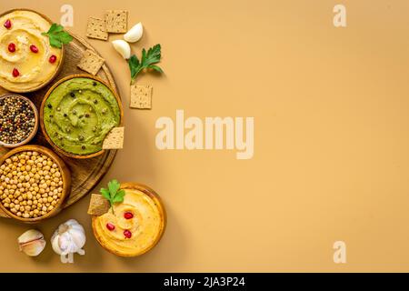 Flatlay von verschiedenen Arten von bunten Hummus in Schalen. Vegane Lebensmittel Hintergrund Stockfoto