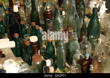 Russland, Izborsk Open Air Museum. Juni 16 2017. Ausstellung der mehrfarbigen antiken Vintage Retro Glasflaschen im Innenhof eines alten Hauses. Stockfoto