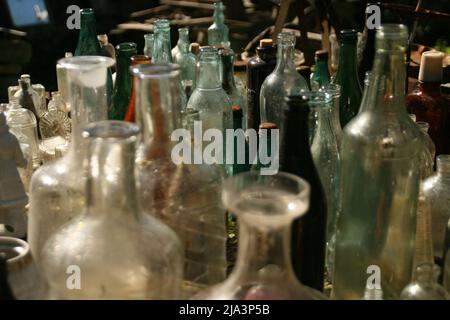Russland, Izborsk Open Air Museum. Juni 16 2017. Ausstellung der mehrfarbigen antiken Vintage Retro Glasflaschen im Innenhof eines alten Hauses. Stockfoto