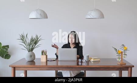 Junge Geschäftsfrau, die eine Videokonferenz mit Kollegen führt und auf den Laptop-Computerbildschirm schaut. Stockfoto