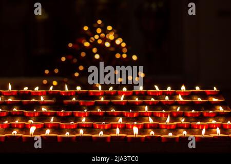 Kerzen werden von Gläubigen im Moment des Gebets für den Frieden in der Kirche angezündet. Gedenktag mit Kerzen. Gedenkkerzen angezündet Stockfoto