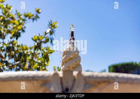 Brunnen. Steinbrunnen, gefüllt mit Wasser und einem Wasserstrahl an seiner Spitze in einem Park in Madrid an einem klaren Tag mit blauem Himmel, in Spanien. Europa. Foto Stockfoto