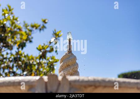 Brunnen. Steinbrunnen, gefüllt mit Wasser und einem Wasserstrahl an seiner Spitze in einem Park in Madrid an einem klaren Tag mit blauem Himmel, in Spanien. Europa. Foto Stockfoto