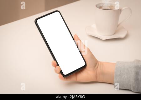 Modup-Telefon. Nahaufnahme Hand hält Handy Smartphone mit leerem Bildschirm im Café. Frau Hand mit imitierten Smartphone im Café Stockfoto