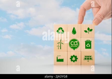 Klimaneutrale langfristige Strategie. Hand setzen Holzwürfel mit grünem Symbol und grünes Symbol auf blauen Himmel Hintergrund. Klimaneutrale nachhaltige Entwicklung Stockfoto