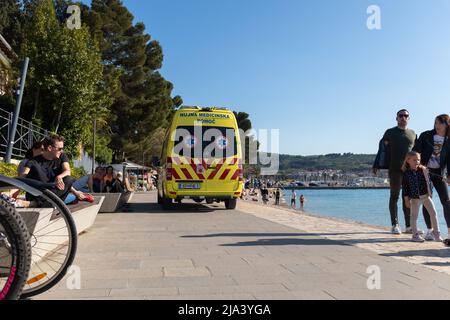 Slowenien, Izola - Juni 5 2021: Ambulanzwagen auf einer belebten Strandstraße voller Menschen im heißen Sommer Stockfoto