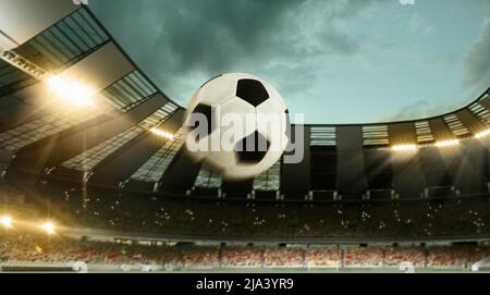 Flug des Fußballballs durch überfülltes Stadion mit Scheinwerfern am Abend. Konzept von Sport, Kunst, Energie, Macht. Unfokus-Effekt Stockfoto