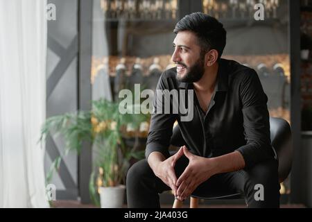 Besitzer eines Weinladens, der vor einer Glasvitrine sitzt. Stockfoto