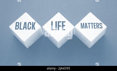 Text von BLM bedeutet, dass Black Lives Matter auf Holzblöcken auf schwarzem Hintergrund geschrieben ist. Stockfoto