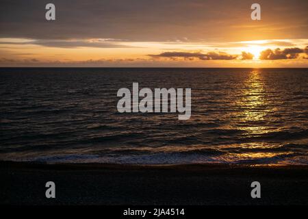 Ruhiges Meer mit Sonnenuntergang Himmel und Sonne durch die Wolken über. Ozean und Himmel Hintergrund. Horizont über dem Wasser. Stockfoto