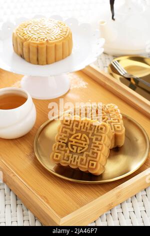 Köstlicher Mooncake, traditioneller chinesischer süßer Snack zum Mid Autumn Festival on the Table, serviert mit Tee Stockfoto