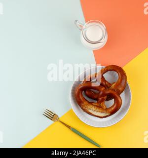 Draufsicht frisch gebackenes, hausgemachtes weiches Pretzel mit Salz auf einem farbenfrohen Tisch. Perfekt für Oktoberfest. Stockfoto