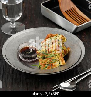Pfannkuchen mit Pajeon- oder koreanischem Schnittlauch, serviert auf dem Teller über dem Holztisch Stockfoto
