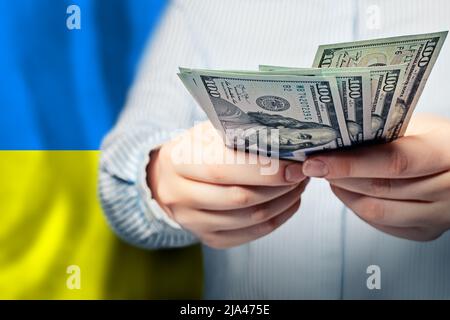 Konzept der ukrainischen Finanzen, Banken und Geld sparen. US-Dollar bar auf der Flagge der Ukraine Stockfoto