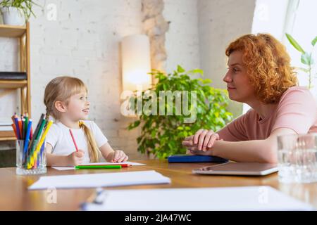 Einzelunterricht im Zentrum der frühen Entwicklung der Kinder. Professionelle Therapeutin kommuniziert mit dem Kind während außerschulischer Aktivitäten. Stockfoto